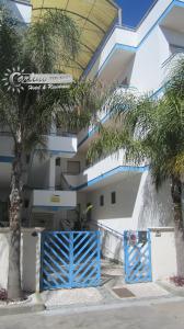 a blue gate in front of a building with palm trees at Appartamenti Baia Verde Gallipoli di Carlino Tourist in Gallipoli