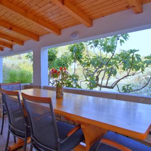 Getaway Beach House في فيلا لوكا: طاولة وكراسي خشبية في غرفة مع نافذة كبيرة