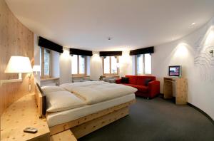 a hotel room with a bed, chair, and nightstand at 3100 Kulmhotel Gornergrat in Zermatt