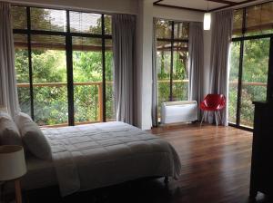 a bedroom with a bed and large windows at Gaze: Entire Modern Tropical Seaview Villa in Pantai Cenang