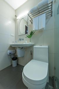 een badkamer met een wit toilet en een wastafel bij Court Meridian Hotel & Suites in Olongapo