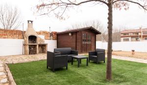un patio con sillas, una mesa y un edificio en La cabaña del bosque, en Villalba de la Sierra