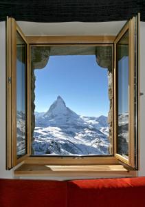 a view through a window of a snowy mountain at 3100 Kulmhotel Gornergrat in Zermatt