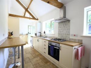 a kitchen with white cabinets and a stove top oven at The Old Dairy in Westbury on Severn +10 photos