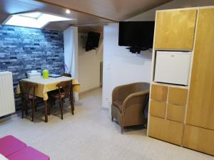 ein Esszimmer mit Tisch, Stühlen und Fernseher in der Unterkunft Hôtel Belair "Ravel Etape" in Weismes