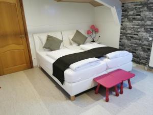 a bedroom with a large white bed with a red stool at Hôtel Belair "Ravel Etape" in Waimes