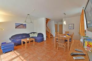 a living room with a blue couch and a table at Ferienhaus An der alten Waldschänke WS-11a in Born