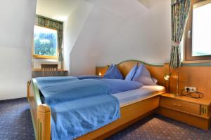 Schlafzimmer mit einem Bett mit blauer Bettwäsche und einem Fenster in der Unterkunft Landgasthof Jagawirt in Krakauschatten