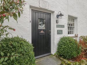 a black door on the side of a white house at Barney's Cottage in Ambleside