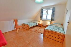 Zimmer mit 2 Betten, einem Stuhl und einem Fenster in der Unterkunft Ferienhaus An der alten Waldschänke WS-11a in Born