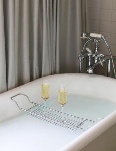 a bathtub with a glass of water next to a sink at Hôtel De Sers Champs Elysées Paris in Paris