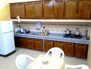 cocina con mesa y nevera blanca en Silia Appartements, en Temara