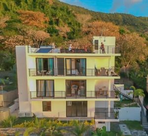 a large yellow house with people standing on the balcony at Fullmoon Apartment & Studio in La Gaulette