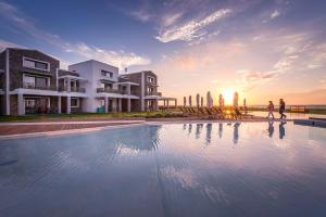 una gran piscina con gente caminando cerca de un edificio en Thalassa Suites en Almiros Beach