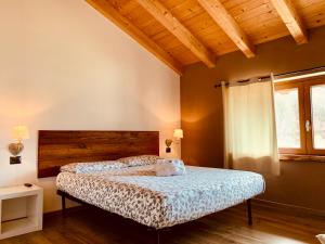 Schlafzimmer mit einem Bett mit einem Kopfteil aus Holz und einem Fenster in der Unterkunft Mortirolo in Mazzo di Valtellina