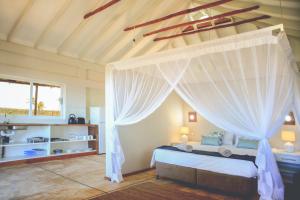 a bedroom with a bed with a canopy at Musica do Mar Beach Front Apartments, Ocean View in Praia do Tofo