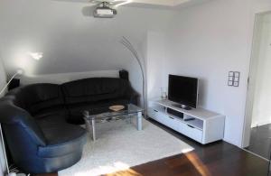 a living room with a black couch and a television at Ferienwohnung Buchbergblick in Coburg