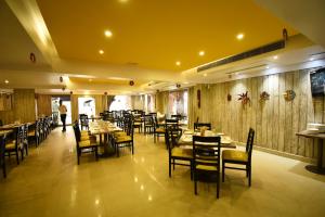 uma sala de jantar com mesas e cadeiras num restaurante em Hotel Campal em Panaji