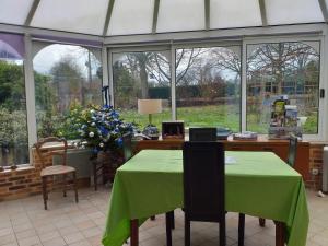 a conservatory with a table with a green table cloth at Ma maison bleue in Saint-Brice-sous-Rânes