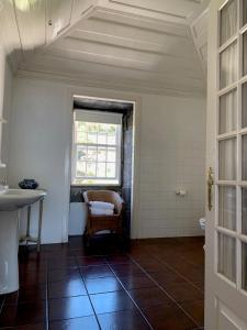 a bathroom with a sink and a window and a chair at Casa das Barcas - TH in São Roque do Pico