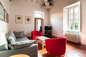a living room with a couch and red chairs at Appartamento nel Parco di Villa Erba in Cernobbio