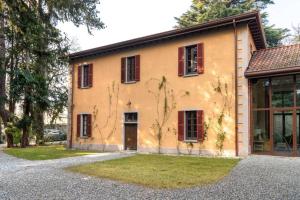 a house with red shuttered windows and a driveway at Appartamento nel Parco di Villa Erba in Cernobbio