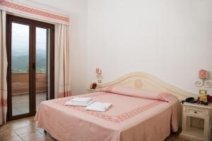 a bedroom with a pink bed with two towels on it at Hotel Montiruju in Santa Maria Coghinas