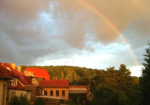 een regenboog in de lucht met huizen en bomen bij Castrum Bucowe in Buckow