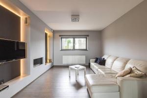 a living room with a white couch and a tv at La Maison de Marie in Borgloon