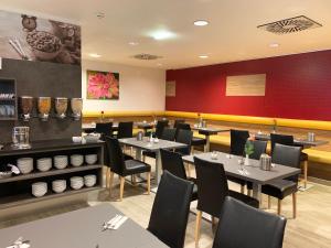 ein Restaurant mit Tischen und Stühlen und einer roten Wand in der Unterkunft Senator Hotel Vienna in Wien