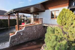 a house with a brick retaining wall and a patio at Gîte chez Patou in Wintzenheim