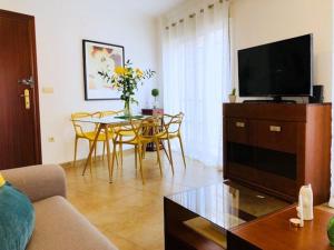 a living room with a television and a table with chairs at Jimena in Fuengirola