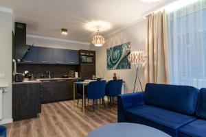 a living room with a blue couch and a kitchen at Apartament Leśny No 4 Blue in Kielce