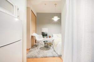 um quarto com uma cama branca e uma cadeira branca em P OIN T - Shinjuku Kabukicho Designer's Apartment I em Tóquio