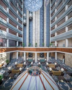 uitzicht op de lobby van een gebouw met tafels en stoelen bij Hotel Duman in Astana