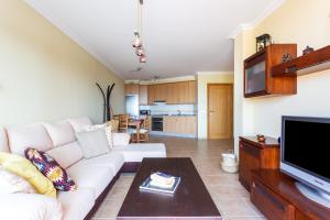 sala de estar con sofá blanco y TV en Home2Book La Tejita Beach, en Granadilla de Abona