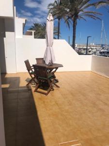 a patio with a table and an umbrella and palm trees at Apartamentos Mar i Vent Puerto de La Savina Formentera in La Savina