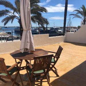 a table and chairs with an umbrella on a patio at Apartamentos Mar i Vent Puerto de La Savina Formentera in La Savina