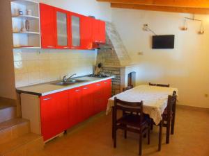 kuchnia z czerwonymi szafkami, stołem i zlewem w obiekcie Getaway Beach House w mieście Vela Luka