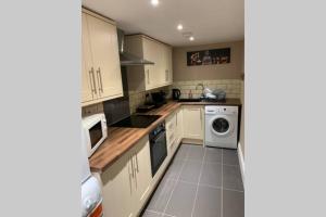 a kitchen with white cabinets and a washer and dryer at a COSY CLEAN GROUND FLOOR FLAT CLOSE TO TOWN CENTRE in Boston