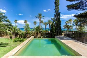 a swimming pool in the backyard of a house with palm trees at TarracoHomes, Villa with Botanic Garden and Private Pool facing the Beach in Miami Platja