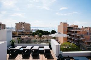 einen Balkon mit Tischen und einem Sonnenschirm auf einem Gebäude in der Unterkunft Terreno Studios in Palma de Mallorca