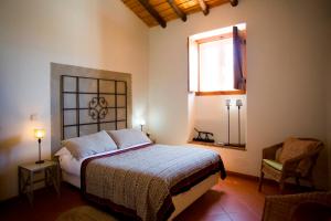 a bedroom with a bed and a window and a chair at Casa dos Castelejos in Guerreiro