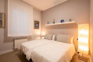 1 dormitorio con cama blanca y ventana en Alameda Recalde Centro en Bilbao
