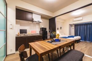 a kitchen and a dining room with a table in a room at IKIDANE Residential Hotel SHIMANOUCHI in Osaka