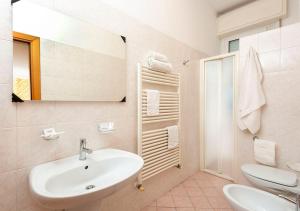 een badkamer met een wastafel, een toilet en een spiegel bij Hotel Petrarca in Rimini