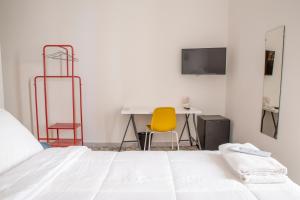ein Schlafzimmer mit einem Bett, einem Schreibtisch und einem gelben Stuhl in der Unterkunft AllYouCanTrip - La Nova in Neapel