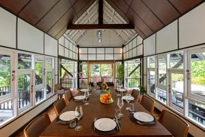 jadalnia ze stołem, krzesłami i oknami w obiekcie Patong Garden House - Luxury Villa in Patong Hills w Patong Beach