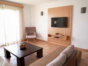 a living room with a couch and a tv on a wall at Appart-hotel La Source in Taghazout