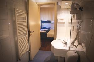 a bathroom with a sink and a mirror and a bed at Hotel Posta in Cecina